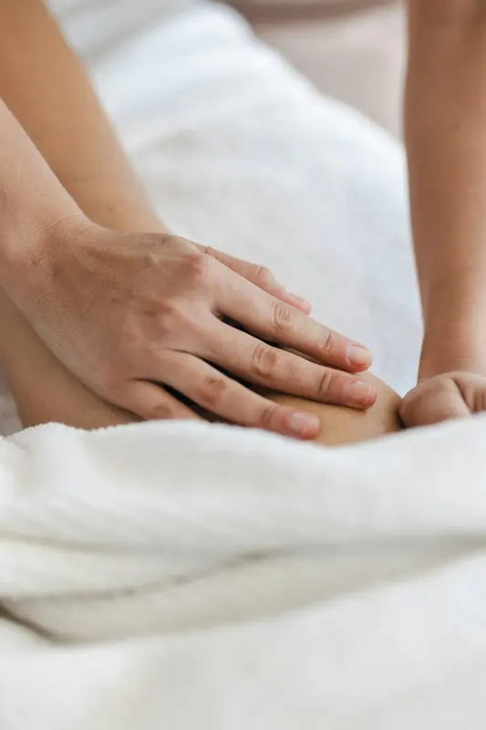 Detalhe de mãos em massagem sobre toalha branca
