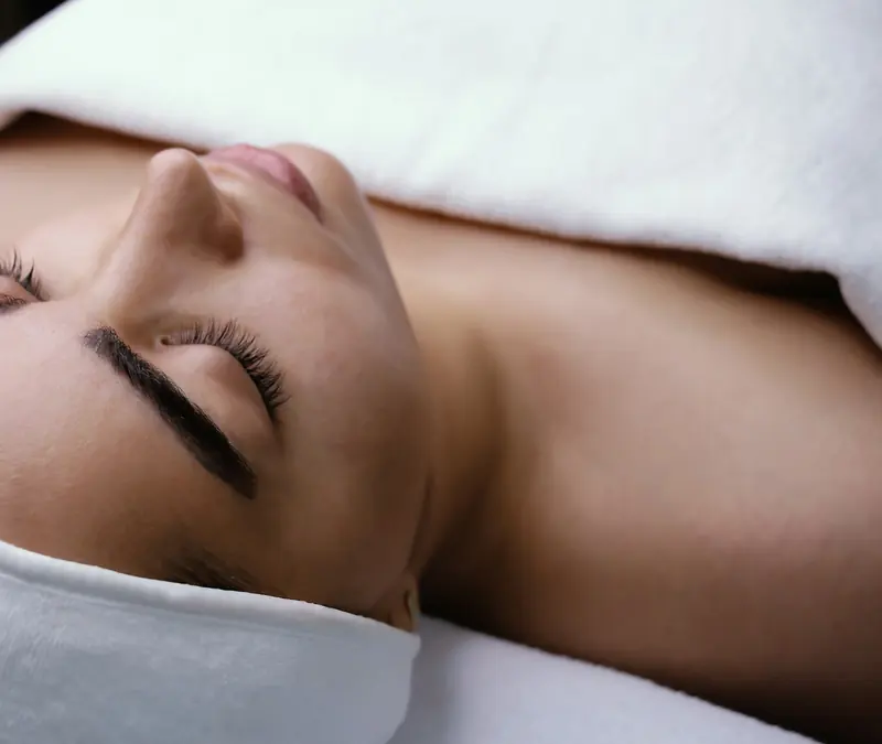 Mulher relaxando de olhos fechados durante um cuidado facial